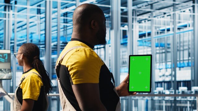Worker using green screen laptop in smart factory, collecting and analyzing data. Expert using tracking software on chroma key notebook in industrial plant equipped with advanced sensors, camera A