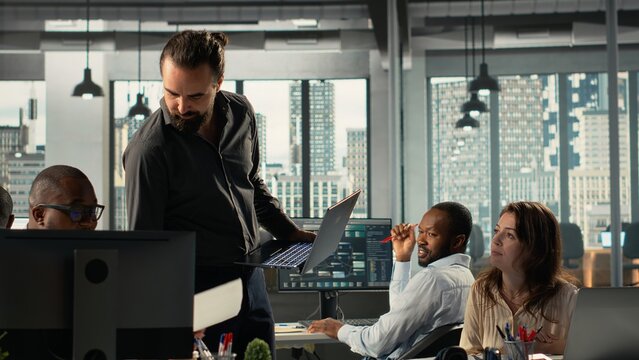 Coworkers engaged in consulting and report sharing at workplace. Professional team reviews visual data and documents to enhance business strategy and performance goals. - Powered by Adobe