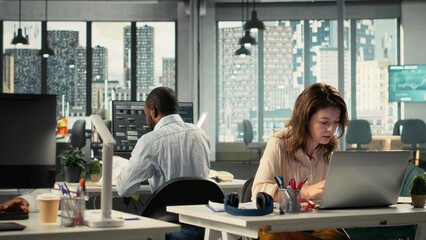 Business people using laptops and computers in bright workspace, analyzing projections, metrics and reports. Team focuses on business intel, insights and targets under executive management.