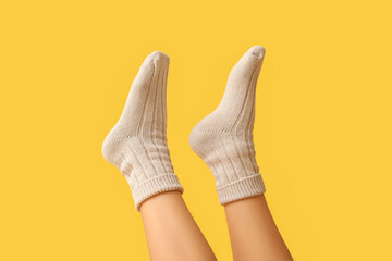 Legs of young woman in cotton socks on yellow background