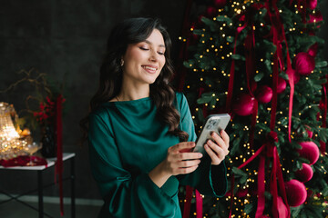 Happy woman using phone at Christmas and New Year party enjoying holiday fun.