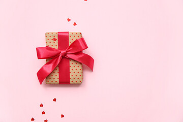 Gift box and heart-shaped sequins for Valentine's Day celebration on pink background