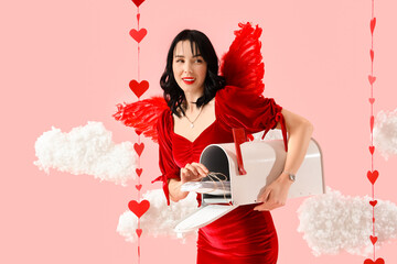 Obraz premium Beautiful young happy woman dressed as cupid with mailbox of love letters in clouds on pink background. Valentine's Day celebration