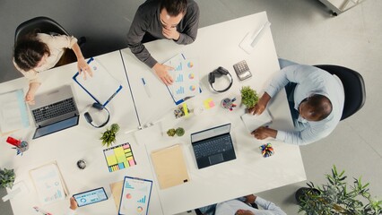 Top down view of company staff engaged in a corporate event for business partnership, coworkers analyze targets and proposals, planning forecasts with stakeholders for investment.