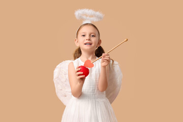 Obraz premium Cute little girl dressed as Cupid with arrow and heart on brown background. Valentine's Day celebration