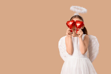 Obraz premium Cute little girl dressed as Cupid with air balloons in shape of heart on brown background. Valentine's Day celebration