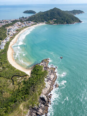 Aerial view of Bombinhas beaches with buildings, sand, rocks and forest