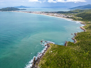 Aerial view of Bombinhas beaches with buildings, sand, rocks and forest