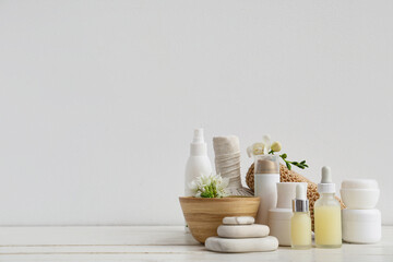 Composition with spa accessories, cosmetic products and flowers on light wooden table