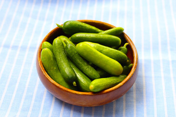 Fresh mini baby cucumbers in wooden bowl