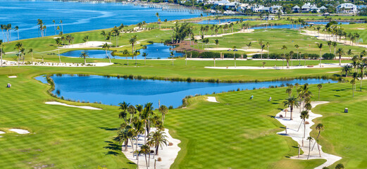 Fototapeta premium Oceanfront golf course in sunny Florida. Outdoor sport grounds with green grass lawns in Boca Grande, small town on Gasparilla Island