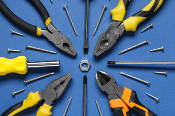 Pliers, screwdrivers and screws on blue background