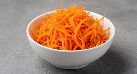 White bowl filled with shredded bright orange carrots on gray textured surface shredded carrots