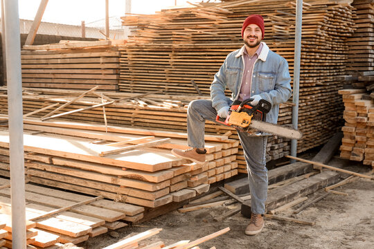 Handsome carpenter with electric saw at sawmill