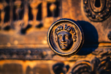Ancient bronze door knob with classical face on historic wooden door