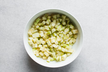 Top view of green apples being sliced on a marble countertop