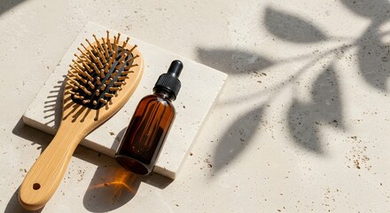 Bamboo hair brush and amber serum bottle on natural stone with leaf shadows for self care concept and daily hair treatment routine