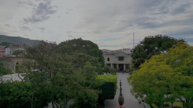 Aerial drone takeoff in downtown Chilpancingo, showing trees, city buildings and mountain skyline