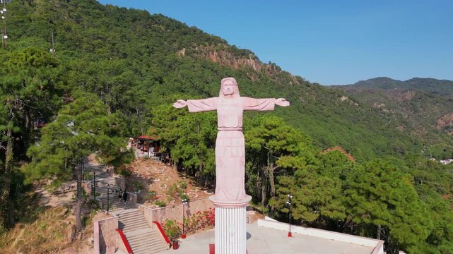 Horizontal dronie shot from Christ statue viewpoint in Taxco, Guerrero, surrounded by green hills