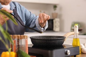 Senior woman spicing fried food in kitchen, closeup