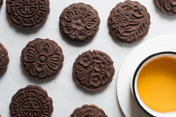 Overhead view of stamped chocolate cookies and a cop of tea on a parchment lined tray