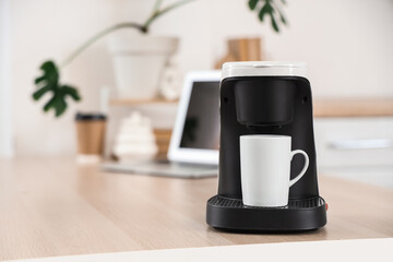 Coffee machine with cup on table in kitchen, closeup