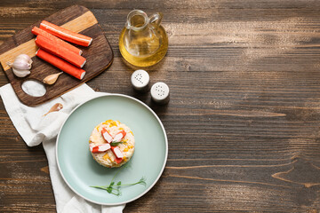 Bowl of salad with crab sticks and corn on wooden background