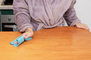 Cleaning the kitchen table while wearing a cozy robe early in the morning