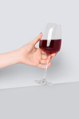 Female hand with glass of red wine on white background