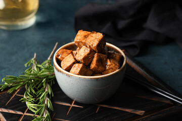 Bowl with pieces of fried tofu cheese and rosemary on dark background