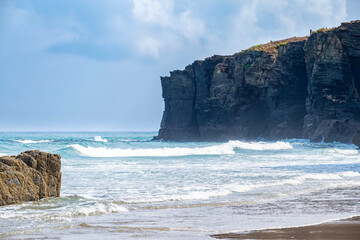 Waves crash against the massive slate cliffs of As Catedrais Beach in Galicia Spain A scenic coastal landscape with wet sand and dramatic rock formations