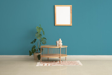 Stylish coffee table with rug, houseplant and photo frame near dark turquoise wall