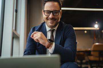 Happy businessman smiling during video call in modern office