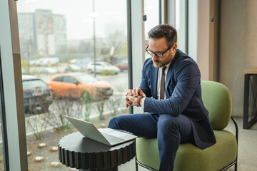 Businessman checking time while waiting for meeting in office