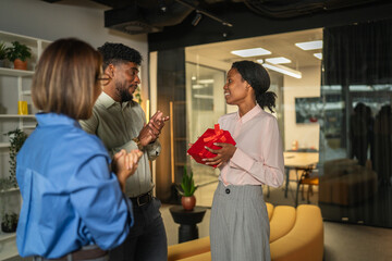 Coworkers celebrating success with gift in office