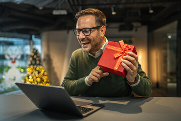 Man receiving gift during video call at home office