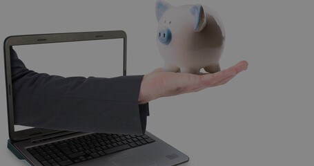 Extending suited arm from laptop screen, holding ceramic piggy bank with blue accents, copy space