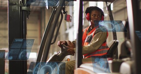Operating forklift, woman wearing orange vest and red earmuffs steering in warehouse, holograms