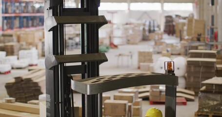 Framing forklift mast or carriage in warehouse, crew in hi-vis checking amber beacon and yellow helm