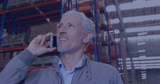 Inspecting senior man wearing gray jacket blue shirt holding smartphone scanning racking in depot