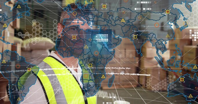 Standing worker wearing yellow safety vest inspecting aisles near stacked boxes with digital map