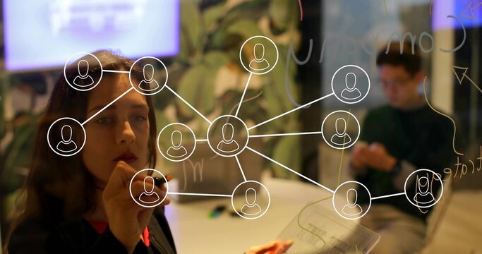 Drawing woman annotating writable glass in meeting room, holding white marker, copy space