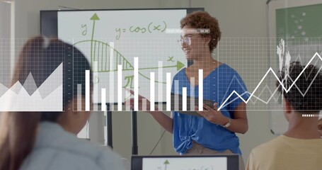 Presenting teacher in blue top with tablet and pointing to whiteboard  and  screens with cosine over