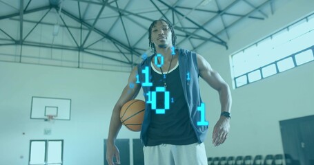 Standing male holding basketball at hip on gym court with hoop, sleeveless top, watch, binary code