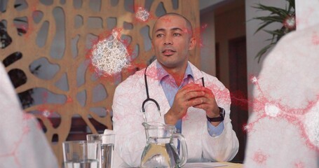 Discussing doctor wearing white lab coat and stethoscope at clinic table with water pitcher