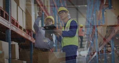 Pointing workers comparing tablet data in aisle, with hardhats, hi-vis vests and digital grid