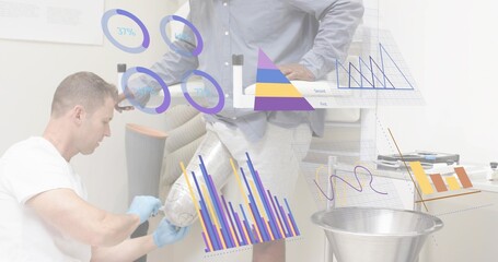 Kneeling tech adjusting wrapped leg in clinic, wearing white tee and blue gloves, digital charts