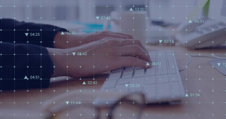 Typing female hands wearing dark sweater pressing keys on white keyboard at desk, showing data grid
