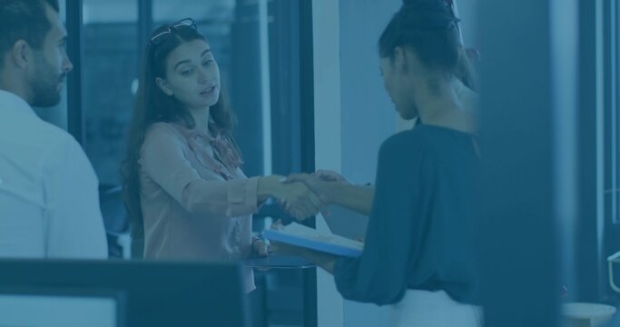 Shaking hands two women in office clothes exchanging documents at reception, holding clipboard