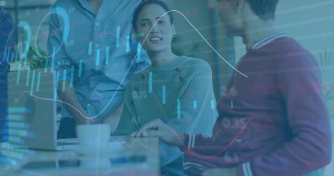 Presenting woman in gray ribbed sweater discussing data at shared workspace, with laptop and charts